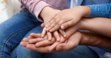 Close-up view of a happy family holding hands. (Shutterstock Photo)