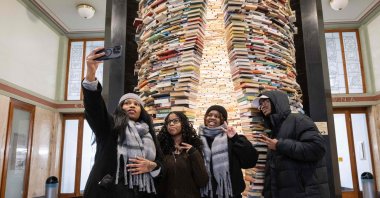 Tourists take a selfie in front of the 'Idiom' art installation made from 8000 books by Slovak artist Matej Kren which is placed in the foyer of the Central Library in Prague, Czech Republic, Jan. 7, 2026. (AFP Photo)