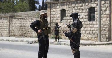 A member of the government security forces (L) speaks with a YPG member during a prisoner exchange, Sheikh Maqsoud neighborhood, Aleppo, Syria, June 2, 2025. (AP Photo)