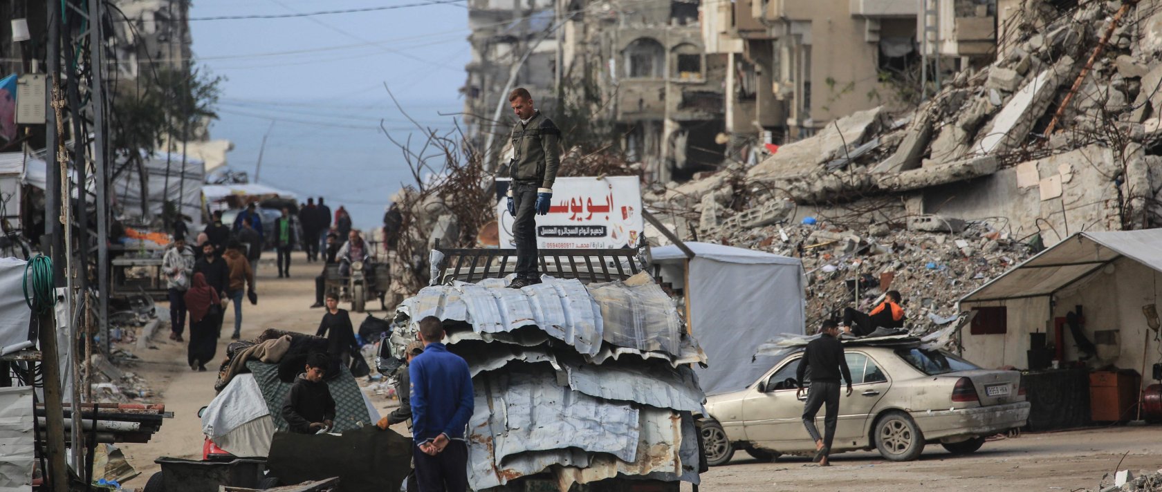 A man stands on a truck loaded with metal sheets as people make their way amid damaged buildings in Jabalia, in the northern Gaza Strip, Jan. 10, 2026. (AFP Photo)