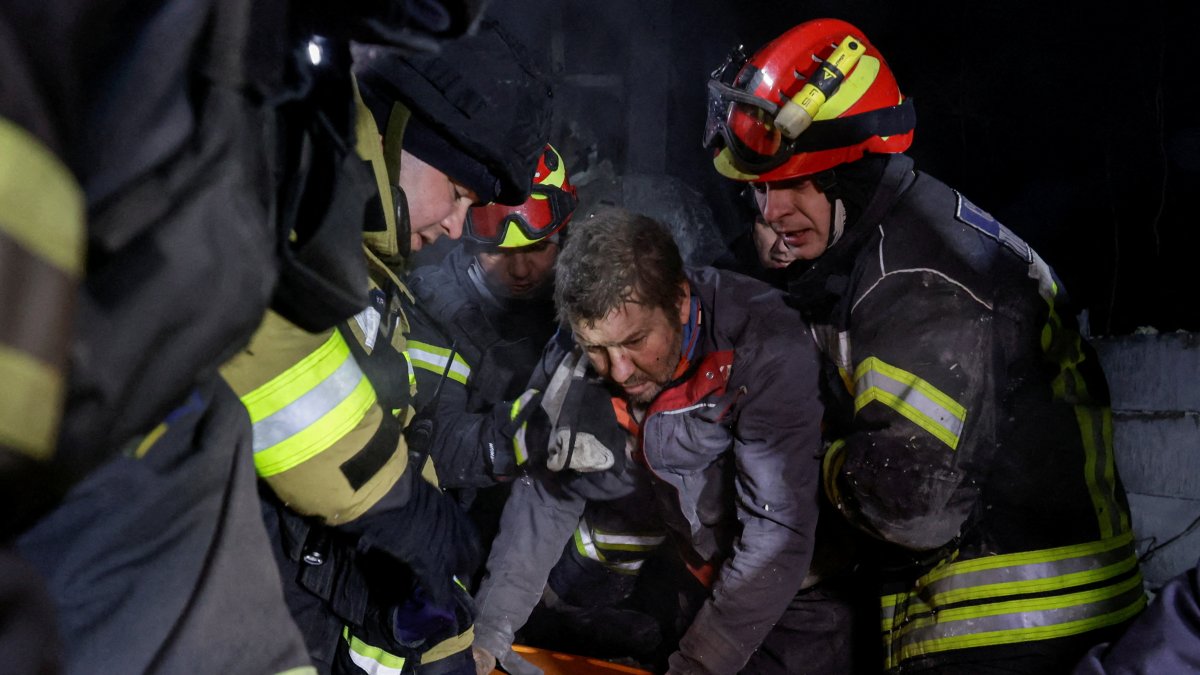 Rescuers assist a man after they rescued him from debris at the site of Russian missile strikes, in Kharkiv, Ukraine, Jan. 13, 2026. (Reuters Photo)