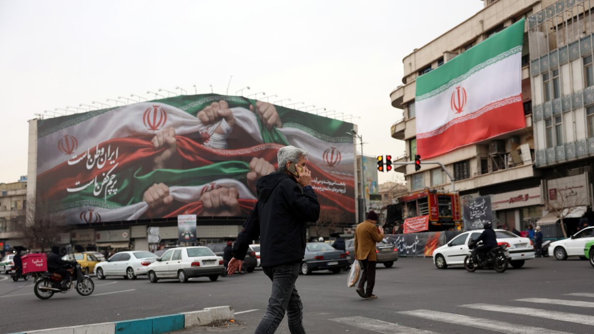 Iranians walk next to a billboard reading 'Iran is our Homeland' at Enqelab Square, Tehran, Iran, Jan. 13, 2026. (EPA Photo)