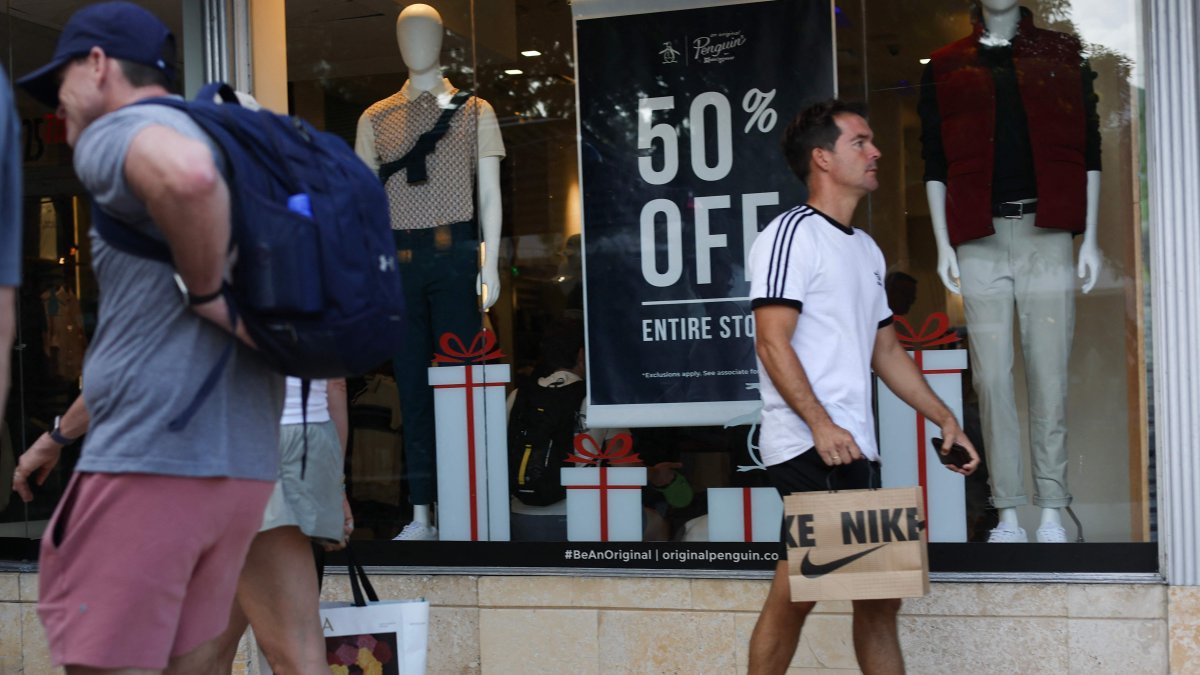 People walk past a sale sign as they visit the Lincoln Road Shopping District two days before Christmas, in Miami, Florida, U.S., Dec. 23, 2025. (AFP Photo)