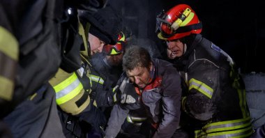 Rescuers assist a man after they rescued him from debris at the site of Russian missile strikes, in Kharkiv, Ukraine, Jan. 13, 2026. (Reuters Photo)