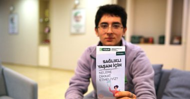 A volunteer holds a Yeşilay awareness booklet while informing residents about addiction prevention during a community outreach activity, Adana, Türkiye, Jan. 13, 2025. (AA Photo)