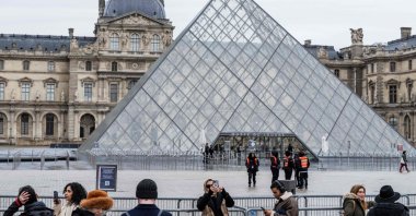 Tourists stand behind barriers blocking access to the Louvre's main courtyard, Paris, France, Jan. 12, 2026. (AFP Photo)