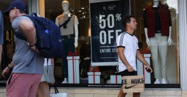 People walk past a sale sign as they visit the Lincoln Road Shopping District two days before Christmas, in Miami, Florida, U.S., Dec. 23, 2025. (AFP Photo)