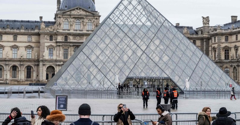 Tourists stand behind barriers blocking access to the Louvre's main courtyard, Paris, France, Jan. 12, 2026. (AFP Photo)