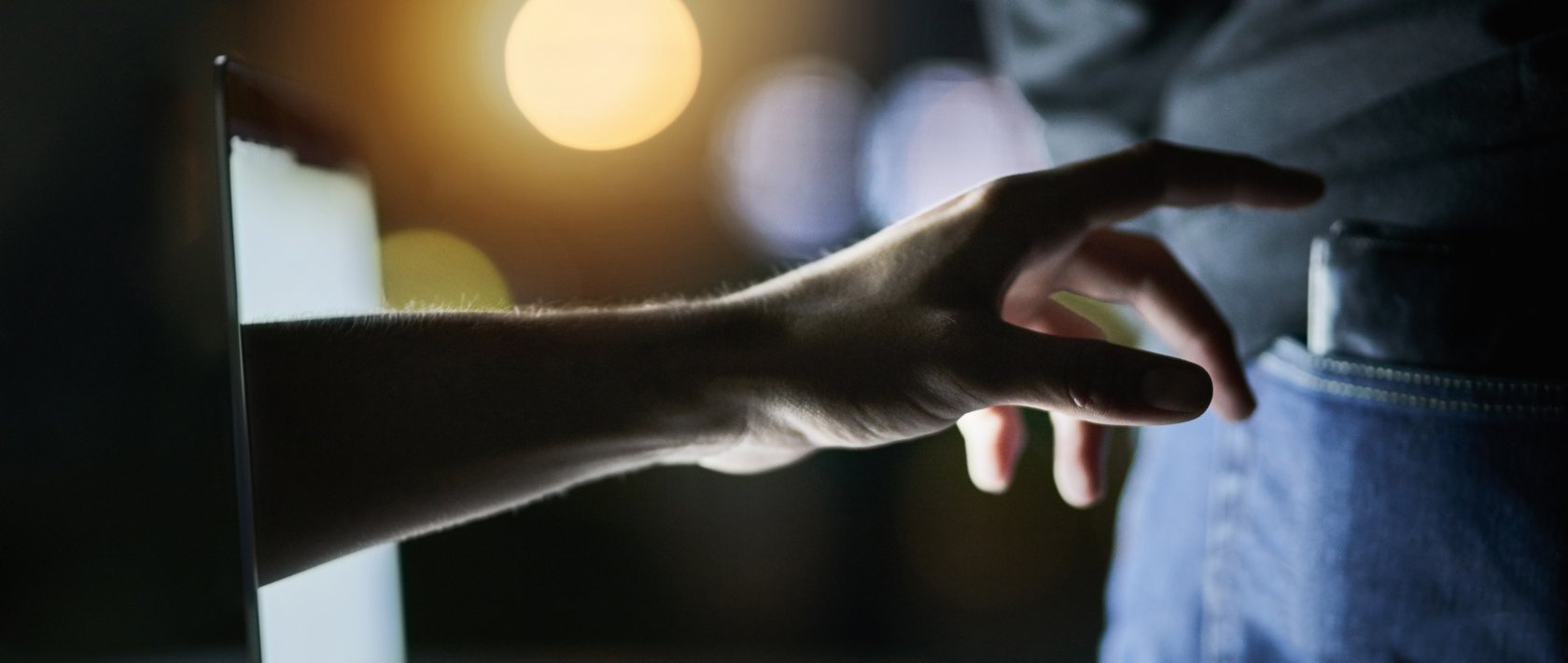 A laptop, a hand and a wallet as the hand attempts to pickpocket a victim. (Shutterstock Photo)