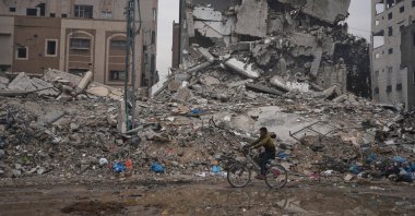 A Palestinian man rides a bicycle past destroyed buildings, Gaza City, Palestine, Jan. 4, 2026. (AP Photo)