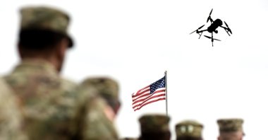 This photo shows American soldiers standing while a drone flyies in the sky. (Shutterstock Photo)