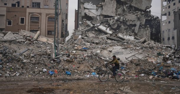 A Palestinian man rides a bicycle past destroyed buildings, Gaza City, Palestine, Jan. 4, 2026. (AP Photo)