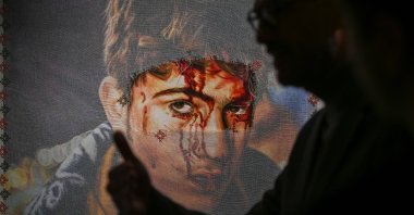 A visitor passes by one of the artworks at the "Posters to the Olive Tree of Exile" exhibition, London, U.K., Jan. 15, 2026. (AA Photo)