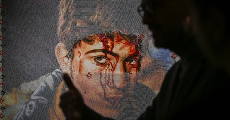 A visitor passes by one of the artworks at the "Posters to the Olive Tree of Exile" exhibition, London, U.K., Jan. 15, 2026. (AA Photo)