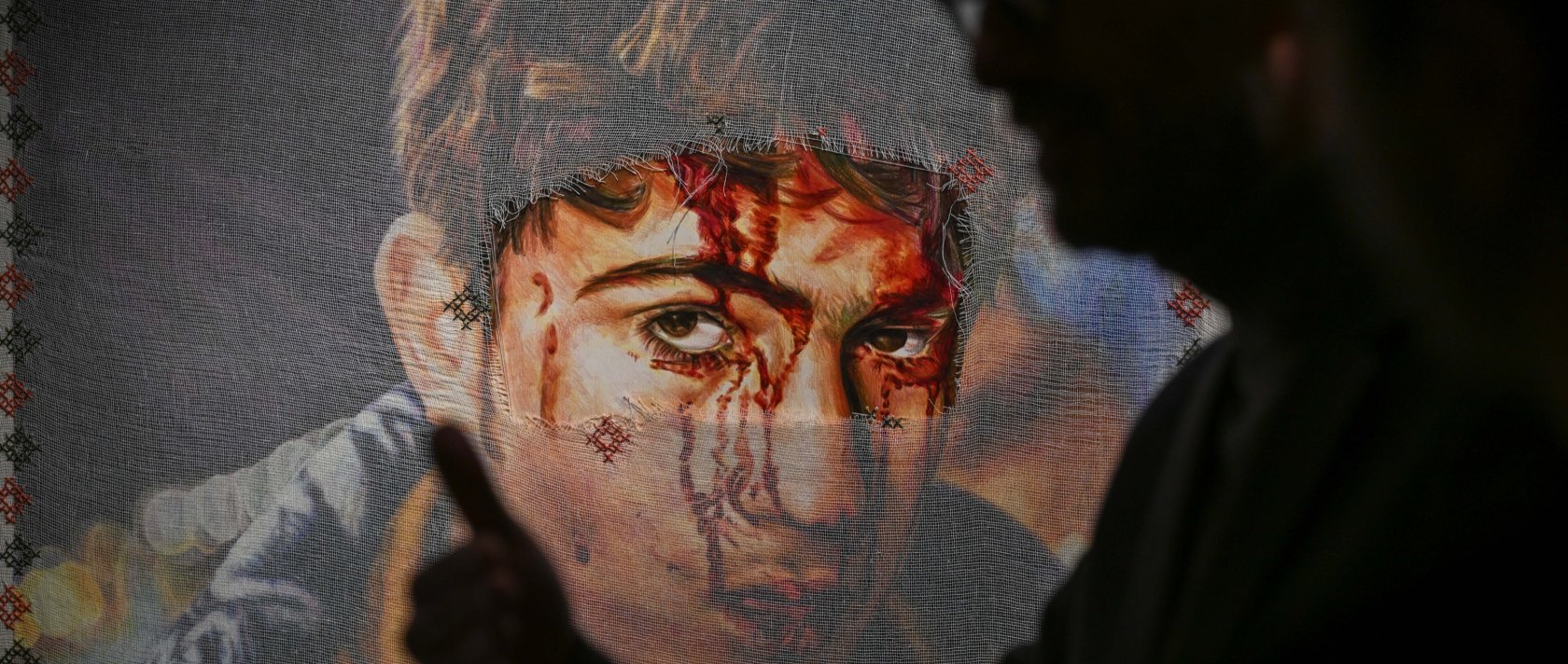 A visitor passes by one of the artworks at the "Posters to the Olive Tree of Exile" exhibition, London, U.K., Jan. 15, 2026. (AA Photo)