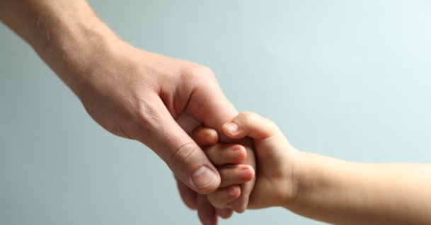 A father and child holding hands. (Shutterstock Photo)
