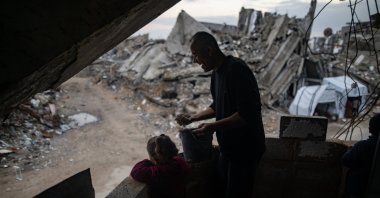 A Palestinian man is assisted by a young family member as he repairs his destroyed home using mud as an alternative to cement, Gaza, Palestine, Jan. 18, 2026. (EPA Photo)