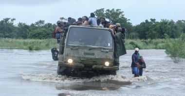 Residents sit on a military truck transporting them across floodwater that blocked a road in the Boane district, Maputo, Mozambique, Jan. 16, 2026. (AFP Photo)