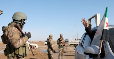A resident waves as Syrian government forces man a checkpoint after entering the city of Ash Shaddadah south of the city of Hassakeh, northeastern Syria, Jan. 20, 2026. (AFP Photo)