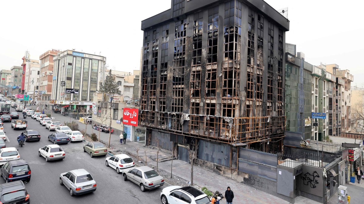 People walk past a building damaged during public protests in Tehran, Iran, Jan. 19, 2026. (AFP Photo)