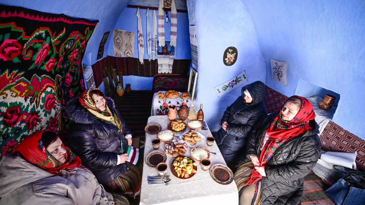 Local women wearing traditional Moldovan clothes sit to eat a meal inside a "basca" museum-house in Rogojeni village, Moldova, Jan. 4, 2026. (AFP Photo)