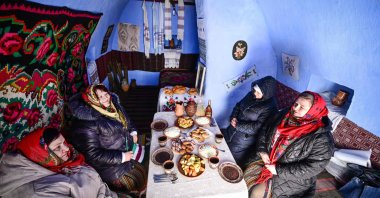 Local women wearing traditional Moldovan clothes sit to eat a meal inside a "basca" museum-house in Rogojeni village, Moldova, Jan. 4, 2026. (AFP Photo)