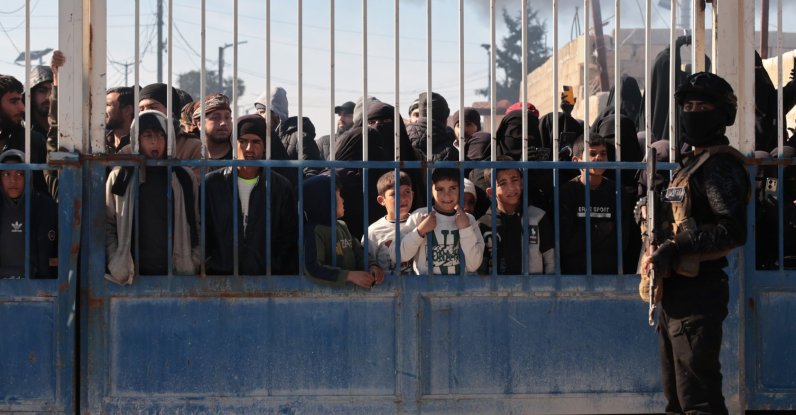 Members of the Syrian security forces stand in front of the gate of the AL-Hol camp, which houses families of suspected Daesh terrorists, after the Syrian government took control of the area, in Hasakah province, Syria, Jan. 21, 2026. (EPA Photo)