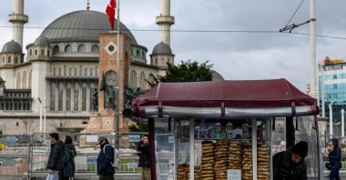 People pass next to a street vendor who sells traditional Turkish bagel "simit," Istanbul, Türkiye, Dec. 27, 2025. (AFP Photo)