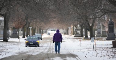 A person walks in a snowy Calvary Catholic Cemetery, Chicago, U.S., Jan. 21, 2026. (AP Photo)
