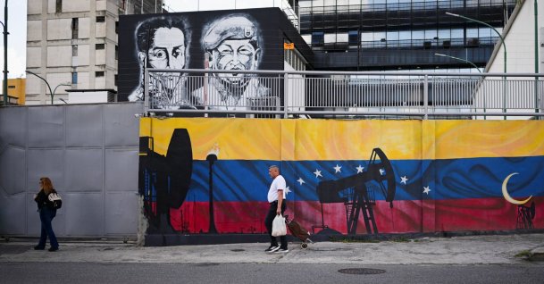 People walk past paintings of oil pumps on Venezuela's national flag and Independence hero Simon Bolivia and late President Hugo Chavez, near the headquarters of Venezuela's state-run oil company PDVSA, Caracas, Venezuela, Jan. 13, 2026. (Reuters Photo)
