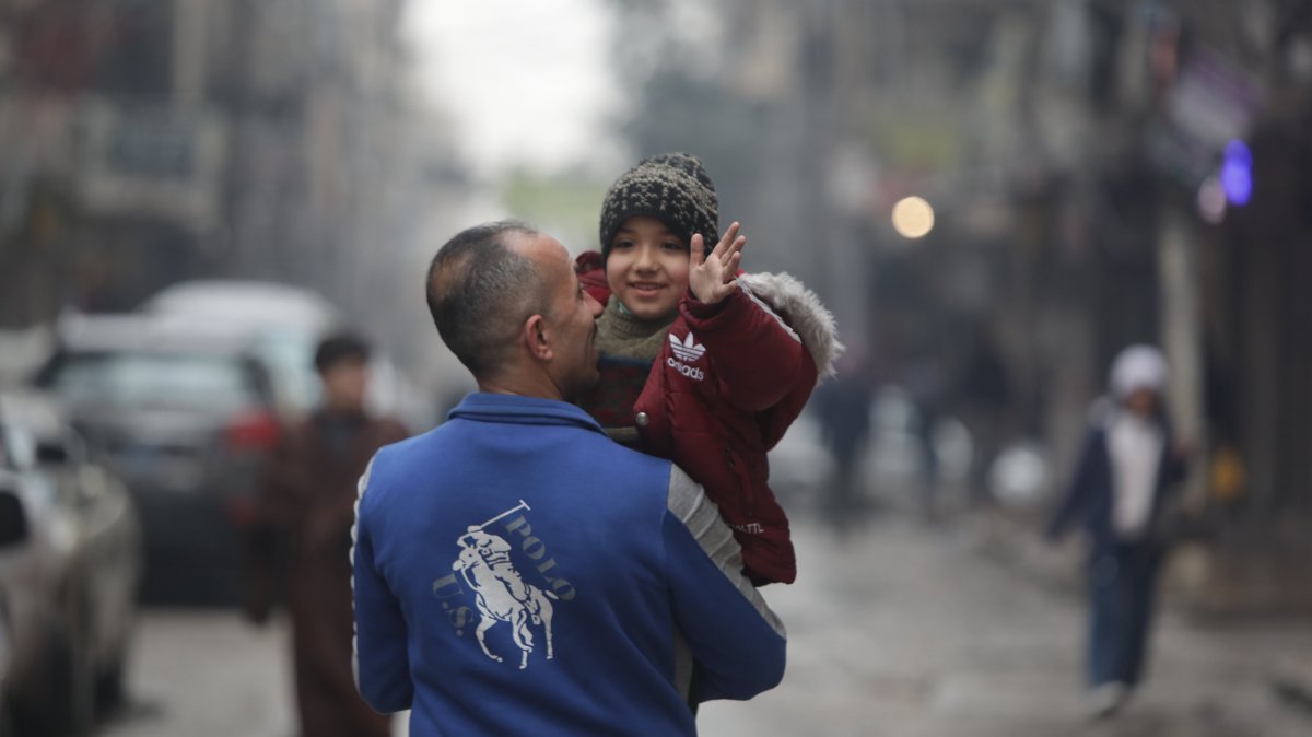A Syrian father and his child walk along a street in the Sheikh Maqsoud neighborhood after the withdrawal of PKK/YPG terrorists, Aleppo, Syria, Jan. 23, 2026. (AA Photo)