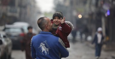 A Syrian father and his child walk along a street in the Sheikh Maqsoud neighborhood after the withdrawal of PKK/YPG terrorists, Aleppo, Syria, Jan. 23, 2026. (AA Photo)