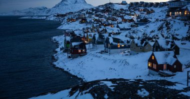 Houses along the coastline are lit as early morning light breaks over the snow-covered hills in Nuuk, Greenland, Jan. 22, 2026. (AFP Photo)