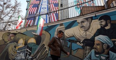 An Iranian man walks near an anti-U.S. and Israel banner hanging at the Palestine square in Tehran, Iran, Jan. 24, 2026. (EPA Photo)