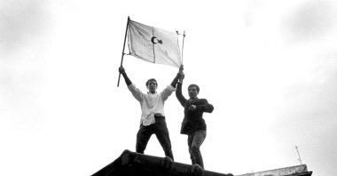 Two men hold the flag of Algeria during the riots for the independence of Algeria, Algiers, Algeria, 1960. (Getty Images Photo)