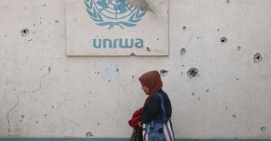 A Palestinian woman walks past a damaged wall bearing the UNRWA logo at a camp for internally displaced people in Rafah, southern Gaza Strip, Palestine, May 28, 202. (AFP Photo)