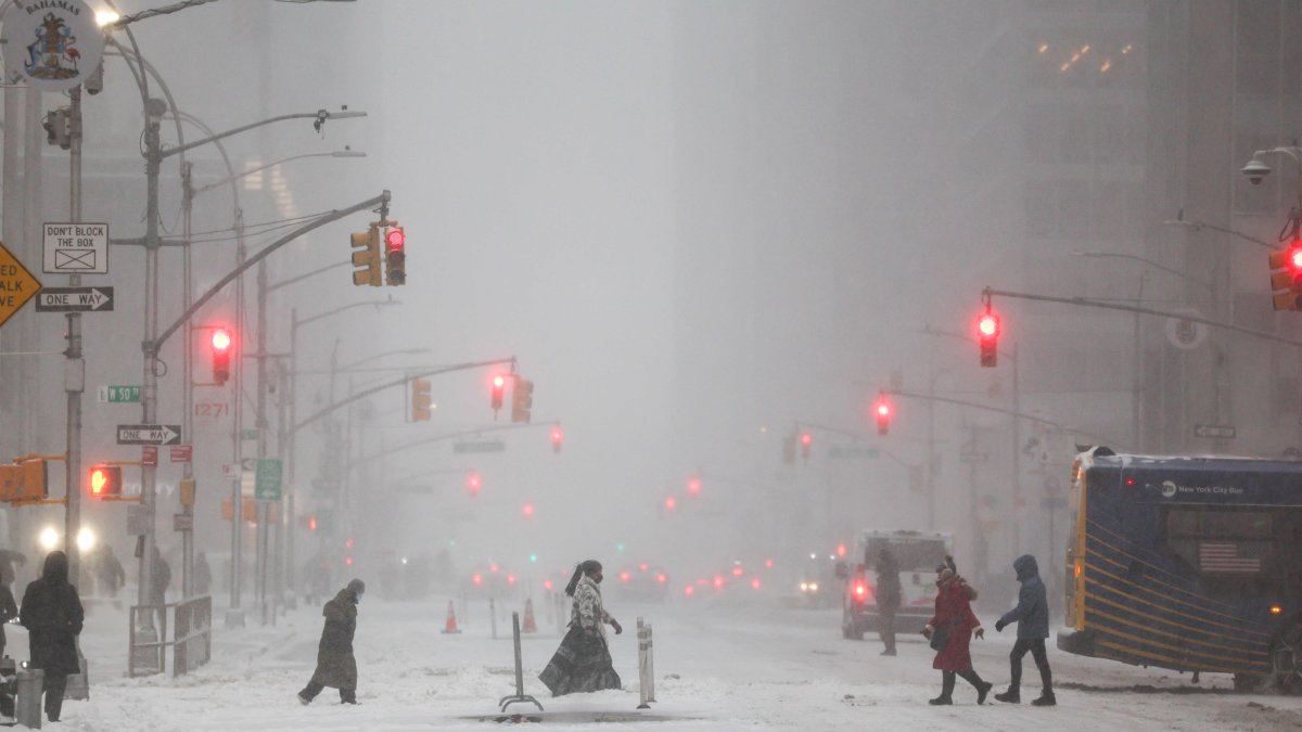 People walk across Sixth Avenue as snow falls in the Manhattan borough, New York City, U.S., Jan. 25, 2026. (AFP Photo)