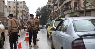 Syrian security officers stand at a checkpoint controlling passing vehicles following a ceasefire, Ashrafiyeh neighborhood, Aleppo, northern Syria, Jan. 11, 2026. (AFP Photo)