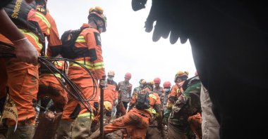 Rescuers try to recover the body of a victim buried by a landslide in Pasirlangu village in Bandung, West Java, Indonesia, Jan. 26, 2026. (AFP Photo)