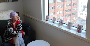 Melek Akkaya sits by the window in her hospital room, looking at photographs of her children, Ankara, Türkiye, Jan. 26, 2026. (DHA Photo)