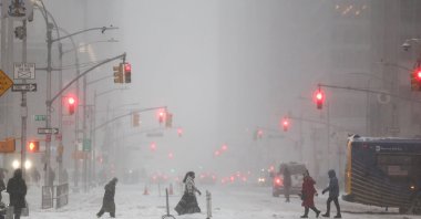People walk across Sixth Avenue as snow falls in the Manhattan borough, New York City, U.S., Jan. 25, 2026. (AFP Photo)