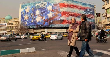 Commuters walk past an anti-U.S. billboard installed on a building at the Enqelab Square in Tehran, Iran, Jan. 26, 2026. (AFP Photo)