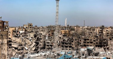 A man fixes a Palestinian flag atop the antenna of a destroyed building that was a clinic for the United Nations Relief and Works Agency for Palestine Refugees (UNRWA) at the Jabalia camp for Palestinian refugees in the northern Gaza Strip, Jan. 19, 2025. (AFP File Photo)