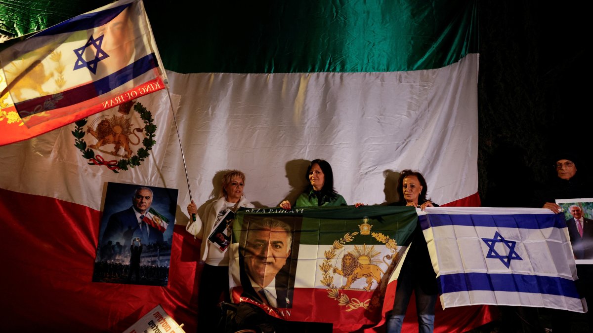 Women hold Israeli flags and pictures of Reza Pahlavi, the exiled son of the last Shah of Iran, while standing next to a huge pre-Iranian Revolution national flag, as Israelis rally in support of the protests happening Iin ran, Holon, Israel, Jan. 14, 2026. (Reuters Photo)