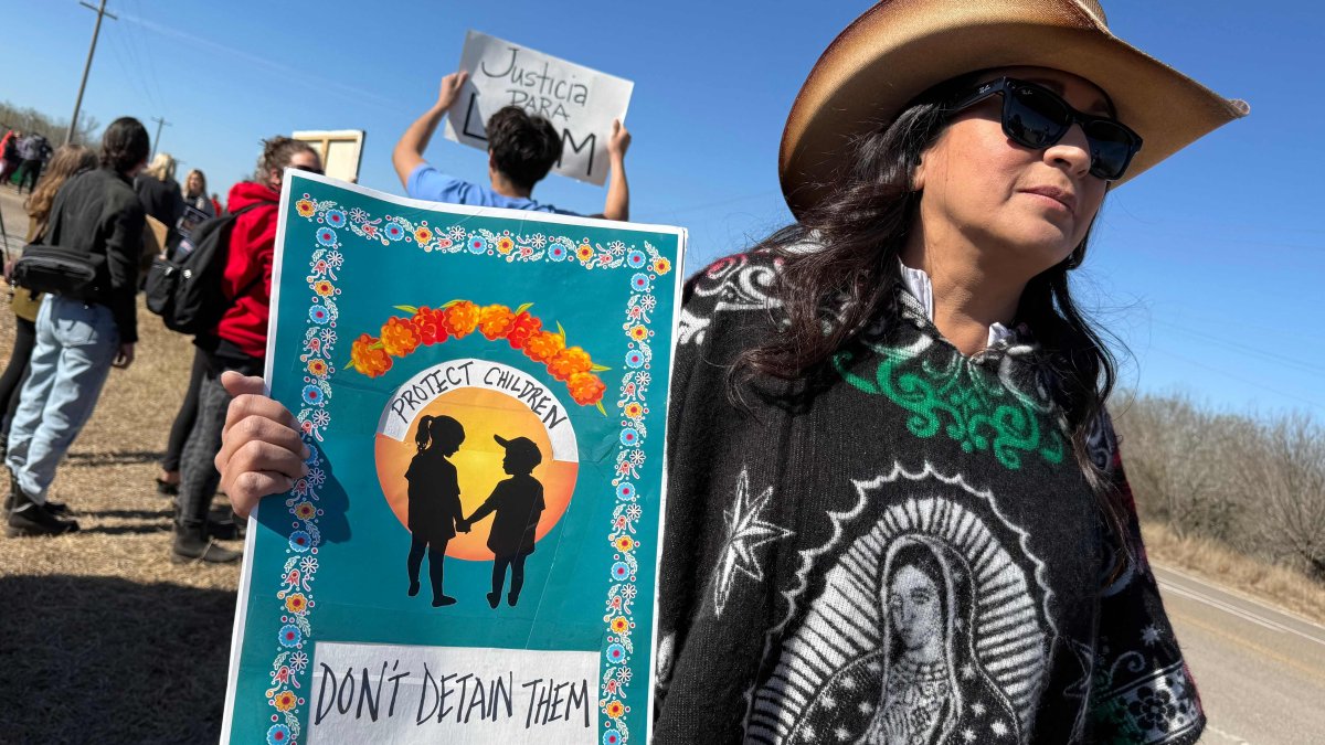 A person holds a sign calling to protect, not detain, children as people gather during a demonstration and vigil outside the South Texas Family Residential Center in Dilley, Texas, U.S., Jan. 28, 2026. (AFP Photo)