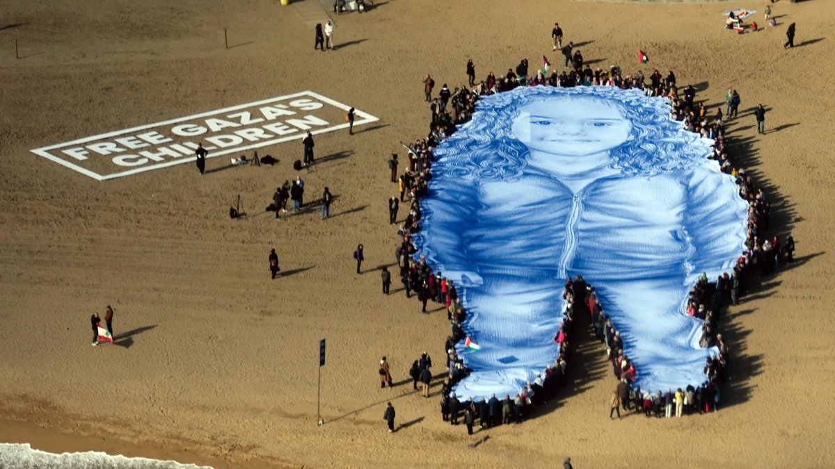 People participate in an action on a beach to remember Hind Rajab (depicted on large figure), a Palestinian girl who died under Israeli fire along with her relatives in 2024, while waiting for emergency services, Barcelona, Spain, Jan. 29, 2026. (EPA Photo)