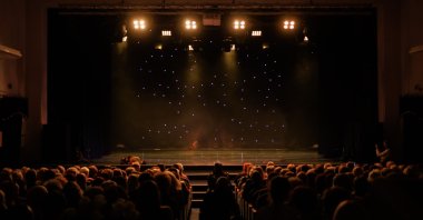 An empty theater stage, illuminated by spotlights and shrouded in smoke before the performance. (Shutterstock Photo)