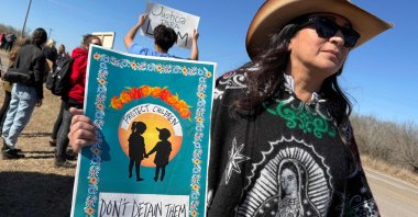 A person holds a sign calling to protect, not detain, children as people gather during a demonstration and vigil outside the South Texas Family Residential Center in Dilley, Texas, U.S., Jan. 28, 2026. (AFP Photo)