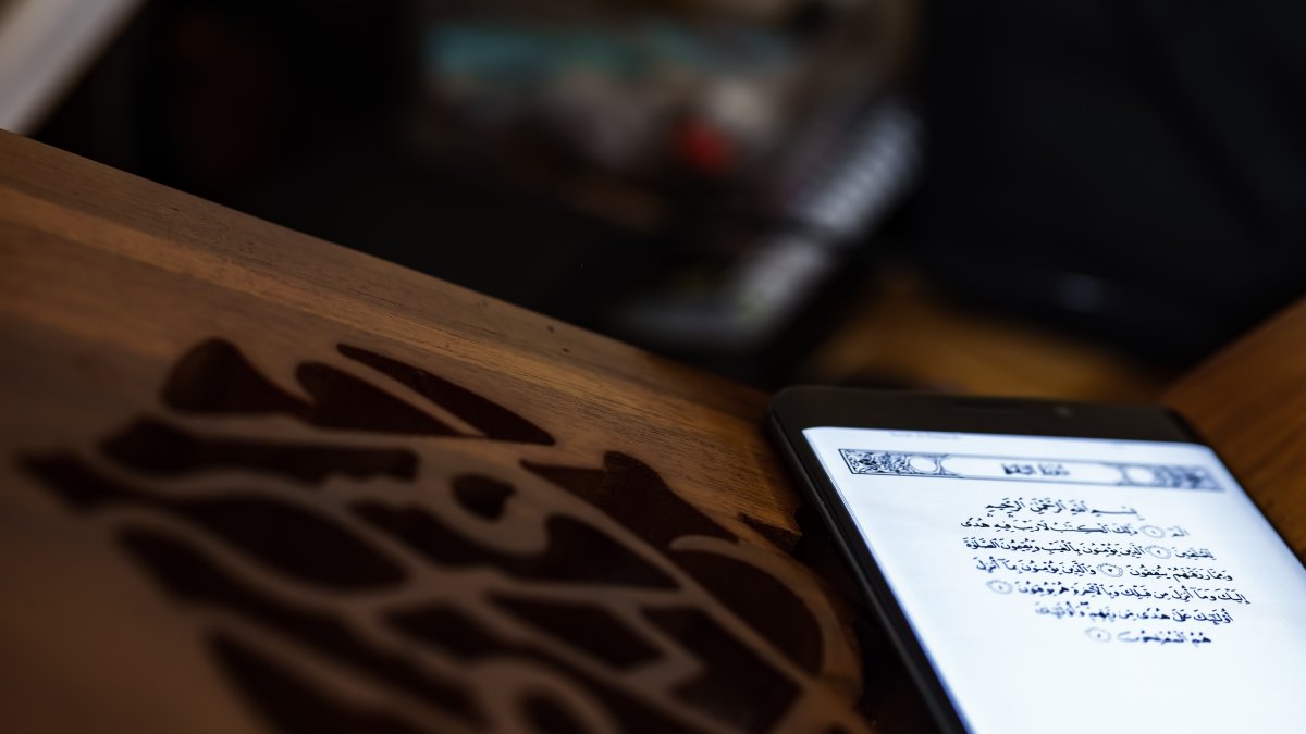 A person reads the Quran on a mobile phone inside a mosque. (Shutterstock Photo) 