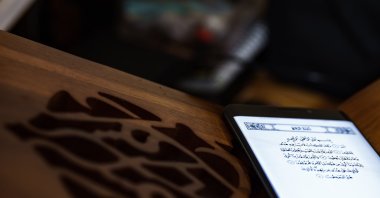 A person reads the Quran on a mobile phone inside a mosque. (Shutterstock Photo) 